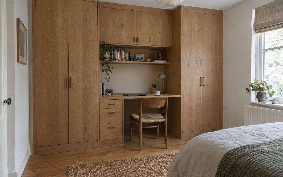 A built-in oak desk between two wardrobe towers in a bedroom corner, design concept