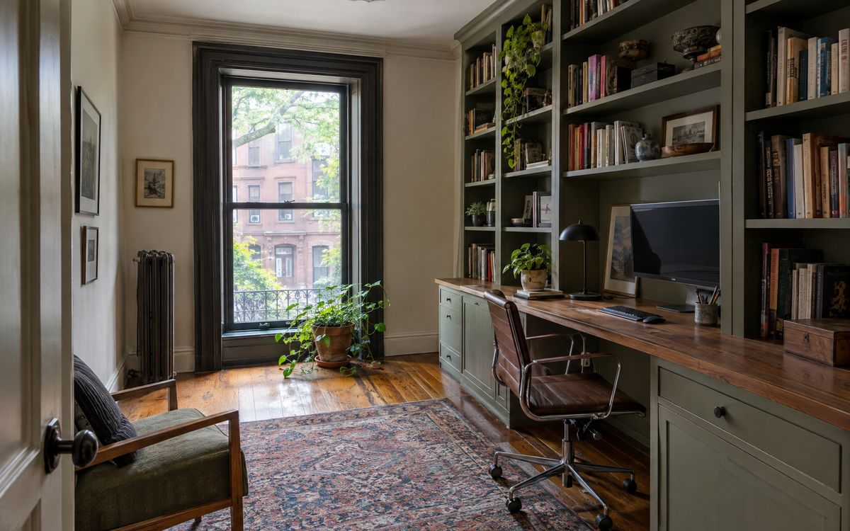 A brownstone spare room turned home office with a built-in desk wall and bookshelves, design concept
